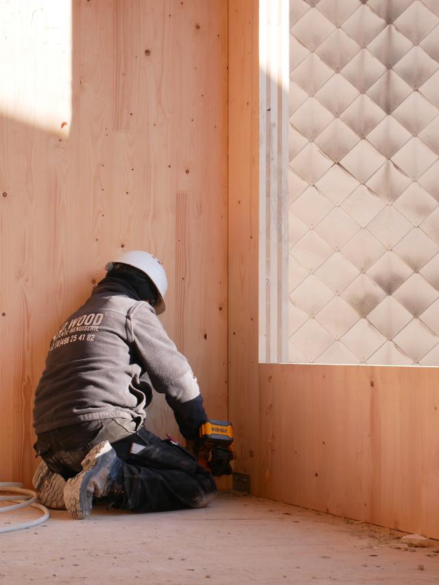 Photo de chantier. Ouvrier en train de visser les éléments CLT