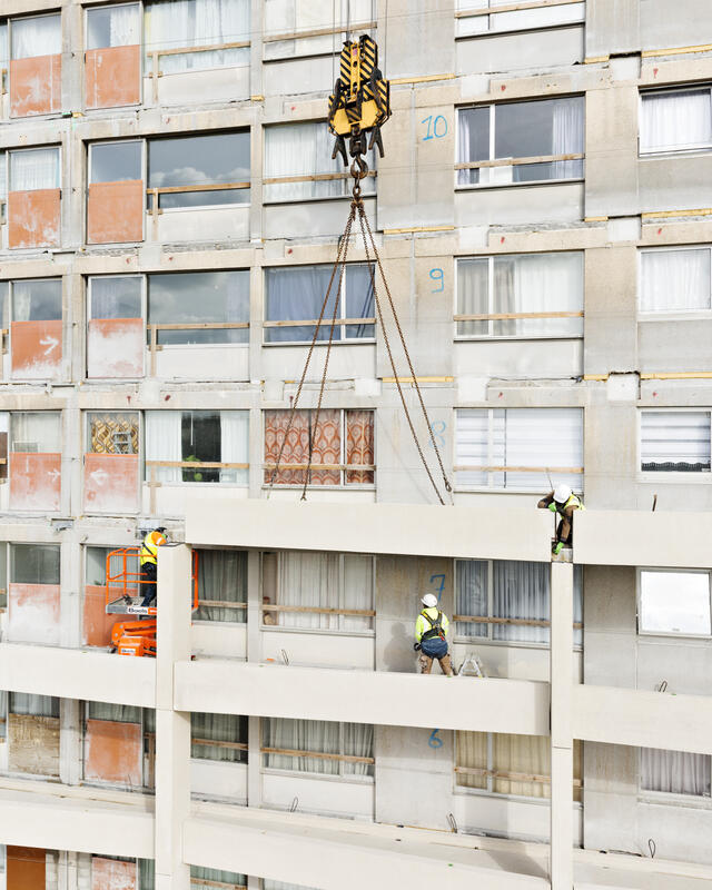 Goujons - Photo de chantier - Phase 2 - Pose d'un balcon avec trois ouvriers à la manoeuvre